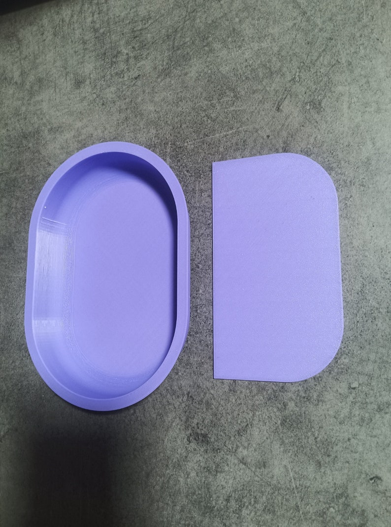 Puede incluir: Dos moldes de silicona p&uacute;rpura para fundici&oacute;n de resina. Un molde es de forma ovalada y el otro es un rect&aacute;ngulo con esquinas redondeadas.