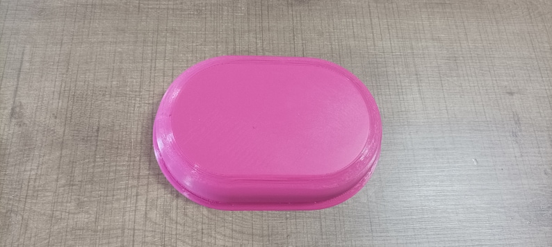 Puede incluir: Una bandeja ovalada de color rosa con una superficie lisa.