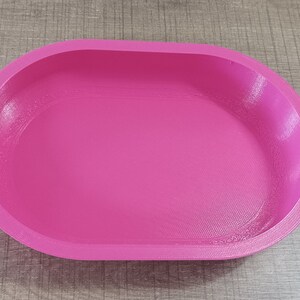 Puede incluir: Un plato ovalado de color rosa brillante hecho de pl&aacute;stico. El plato est&aacute; vac&iacute;o y tiene una superficie lisa.