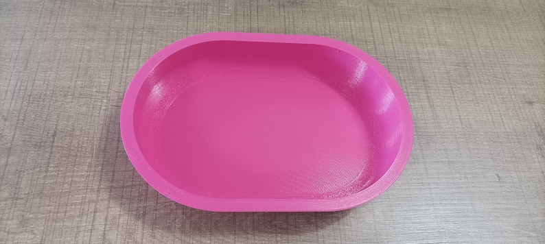 Puede incluir: Un plato ovalado de color rosa brillante hecho de pl&aacute;stico. El plato est&aacute; vac&iacute;o y tiene una superficie lisa.