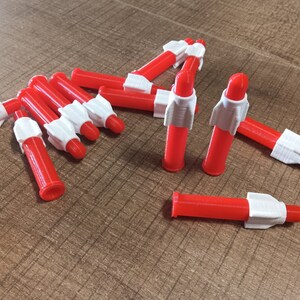 Puede incluir: Un grupo de diez cohetes de juguete de pl&aacute;stico rojo y blanco. Los cohetes miden aproximadamente 10 cm de largo y tienen una punta blanca y un cuerpo rojo.