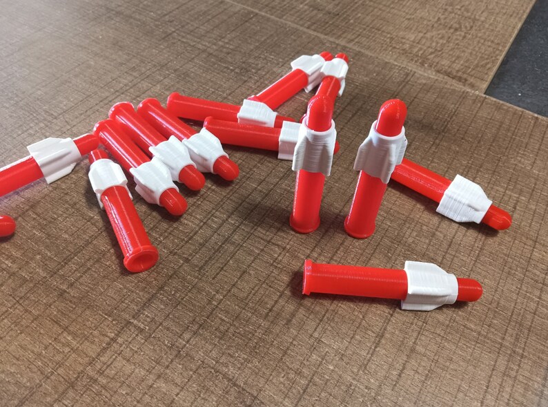 Puede incluir: Un grupo de diez cohetes de juguete de pl&aacute;stico rojo y blanco. Los cohetes miden aproximadamente 10 cm de largo y tienen una punta blanca y un cuerpo rojo.