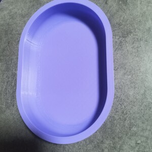 Puede incluir: Un plato ovalado de color lila claro con una superficie lisa ligeramente texturizada. El plato est&aacute; hecho de un material suave y flexible, posiblemente silicona.