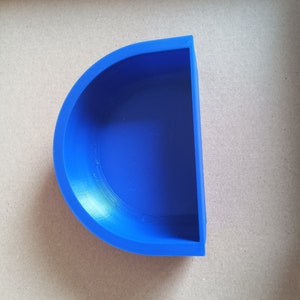 May include: A blue plastic half-circle dish. The dish is empty and has a smooth, slightly shiny surface.