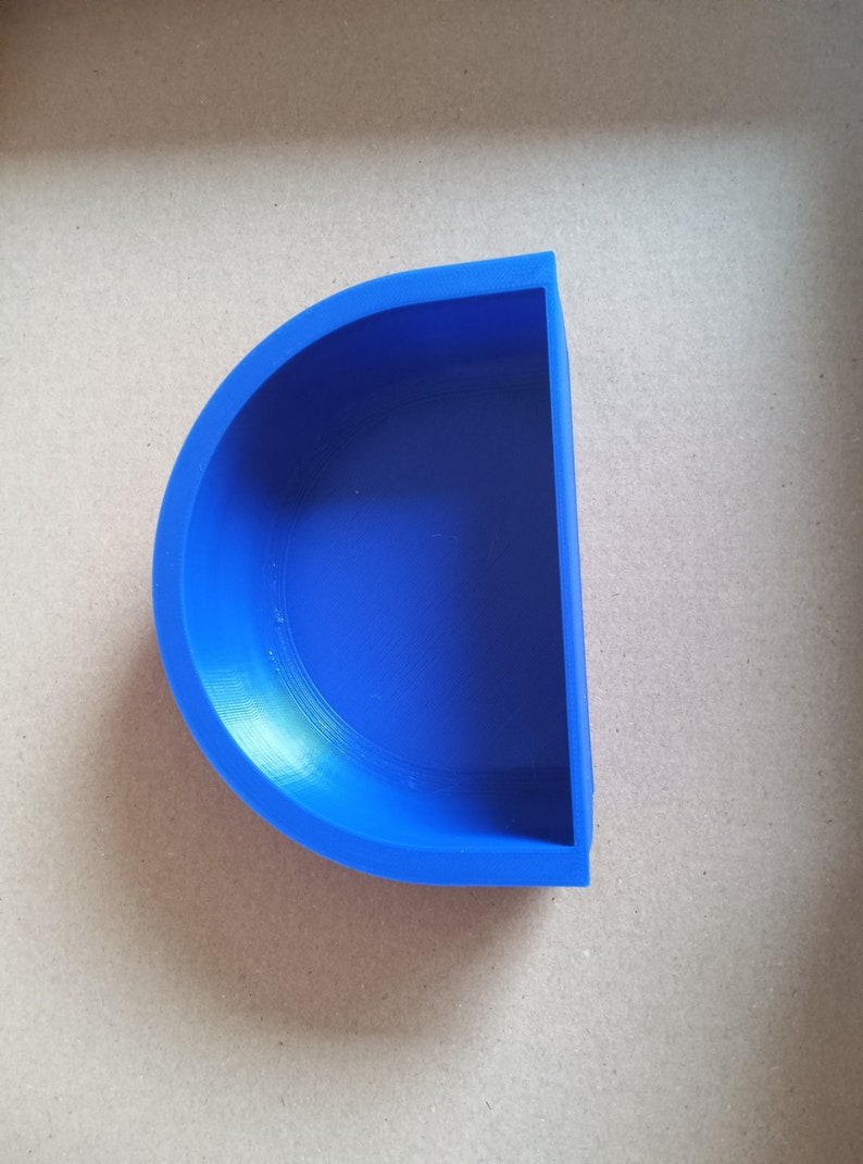 May include: A blue plastic half-circle dish. The dish is empty and has a smooth, slightly shiny surface.