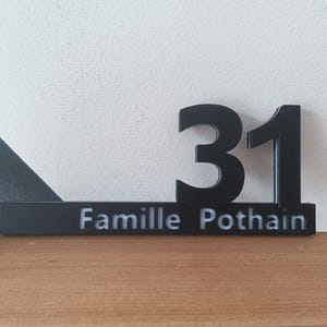 May include: Black house number sign with the number 31 and the text "Famille Pothain" in white.