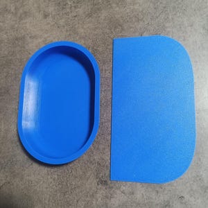 Puede incluir: Dos herramientas de horneado de silicona azul. Una es un raspador rectangular y la otra es un molde ovalado.