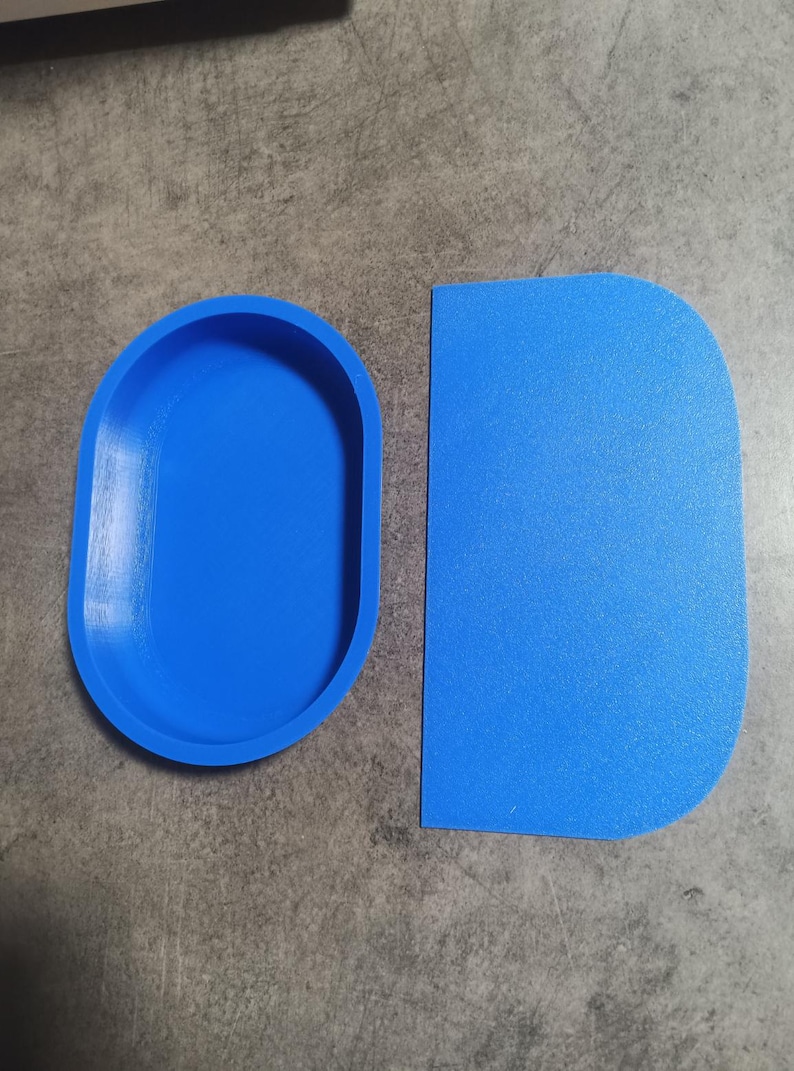 Puede incluir: Dos herramientas de horneado de silicona azul. Una es un raspador rectangular y la otra es un molde ovalado.