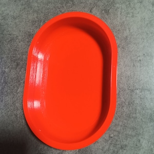 Puede incluir: Un plato ovalado de color naranja brillante hecho de pl&aacute;stico. El plato es liso y tiene un acabado brillante.