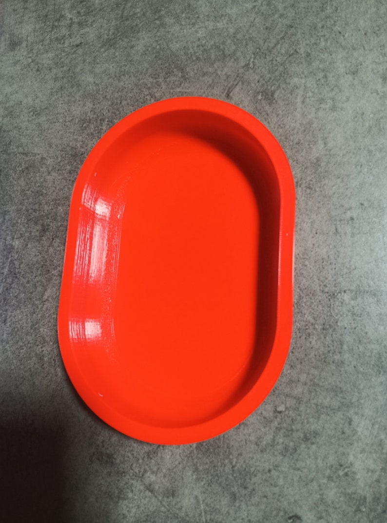 Puede incluir: Un plato ovalado de color naranja brillante hecho de pl&aacute;stico. El plato es liso y tiene un acabado brillante.