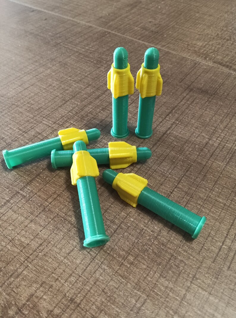 Puede incluir: Cinco puntas de dardos de pl&aacute;stico verde y amarillo. Las puntas tienen forma de cohete y tienen una punta amarilla y un cuerpo verde.