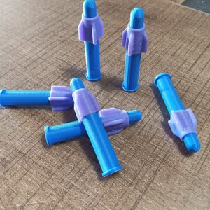 Puede incluir: Cinco objetos de pl&aacute;stico en forma de cohete, azules y morados. Los objetos est&aacute;n sobre una superficie de madera.