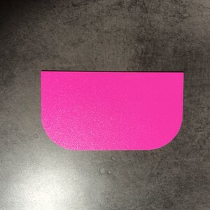May include: A bright pink plastic scraper with rounded edges. The scraper is designed for spreading frosting or icing on cakes and other baked goods.