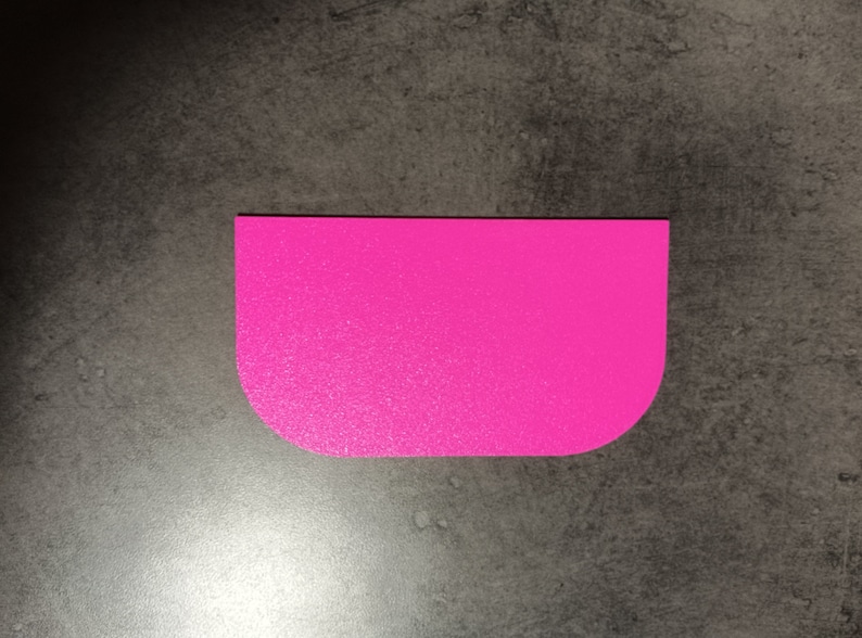 May include: A bright pink plastic scraper with rounded edges. The scraper is designed for spreading frosting or icing on cakes and other baked goods.