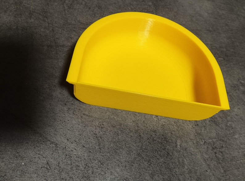 May include: A bright yellow plastic dish with a curved, rounded shape. The dish is designed to hold small items.