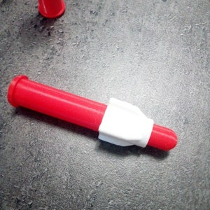 Puede incluir: Una boquilla de pl&aacute;stico roja y blanca para una pistola de pegamento. La boquilla mide aproximadamente 12,5 cm de largo y tiene una punta blanca.
