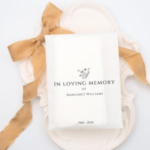 May include: White paper bag with a floral design and the text "In Loving Memory of Margaret Williams 1960-2024".