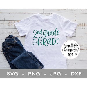 Puede incluir: Una camiseta blanca con el texto "2nd grade GRAD" en letras verde turquesa. La camiseta está sobre un fondo de madera blanca con un par de pantalones vaqueros azules doblados a su lado. Un pequeño círculo con el texto "Small Biz Commercial Use" está en la esquina inferior derecha.