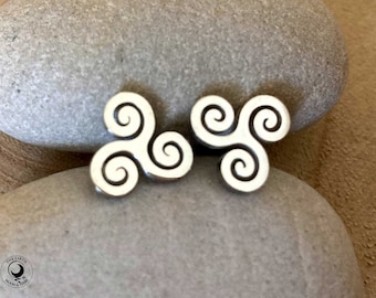 May include: A pair of silver earrings with a triple spiral design. The earrings are on a gray stone background.
