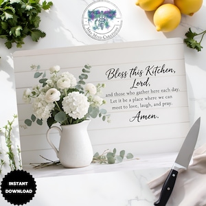 May include: White cutting board with the text "Bless this Kitchen, Lord." A white pitcher holds white flowers and greenery. A black-handled knife rests on the right. Lemons and herbs are in the background. The words "Instant Download" are in the lower left.