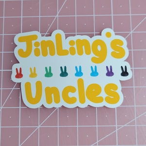 May include: A yellow sticker with the text "JinLing's Uncles" in a rounded font. There are eight small rainbow colored bunny silhouettes below the text.
