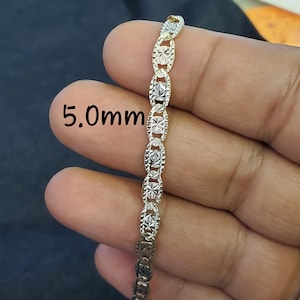 May include: A two-tone gold chain necklace with a 5.0mm width. The chain is made of oval links with a diamond-cut design.