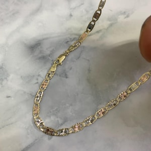 K&ouml;nnte beinhalten: Eine goldene Kettenkette mit einem Ankerketten-Design. Die Kette besteht aus drei verschiedenen Goldfarben: Gelb, Wei&szlig; und Rotgold.