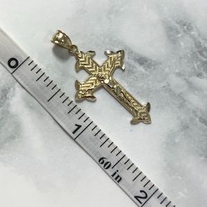 May include: A gold-toned cross pendant with a detailed design and a figure of Jesus Christ. The pendant is approximately 1 inch in length.