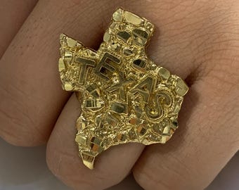 May include: A gold ring shaped like the state of Texas with the word "TEXAS" embossed on the ring.