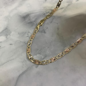 K&ouml;nnte beinhalten: Eine goldene Kettenkette mit dreifarbigem Design. Die Kette besteht aus drei verschiedenen Goldfarben: Gelb, Wei&szlig; und Rotgold.
