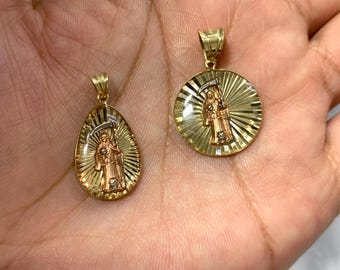 May include: Two gold pendants featuring a depiction of the Grim Reaper. The pendants are in the shape of an oval and a circle. Both pendants have a textured, sunburst design.