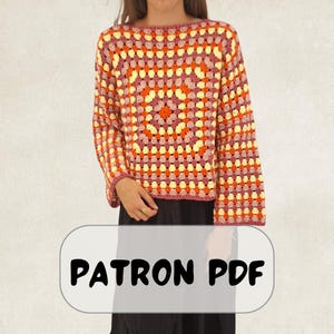 May include: A long-sleeved crochet jumper featuring a multi-coloured granny square pattern in shades of orange, yellow, and dark pink. The garment has a round neckline and a loose fit. A rectangular overlay at the bottom displays the text PATRON PDF.