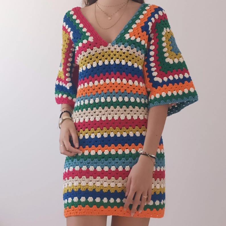 May include: A colorful crochet dress with a rainbow striped pattern. The dress has a v-neck and short sleeves.