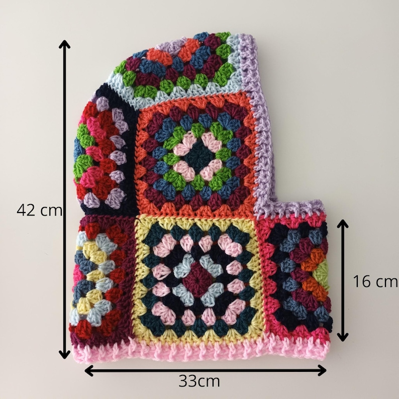 May include: A colourful crocheted hat with a granny square pattern. The hat is 16 cm tall and 33 cm wide. It is made with a variety of colours, including red, green, blue, yellow, and pink.