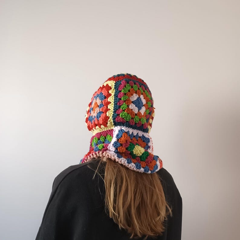 May include: A colourful crocheted hat and neck warmer with a granny square pattern in shades of red, orange, yellow, green, blue, and pink.