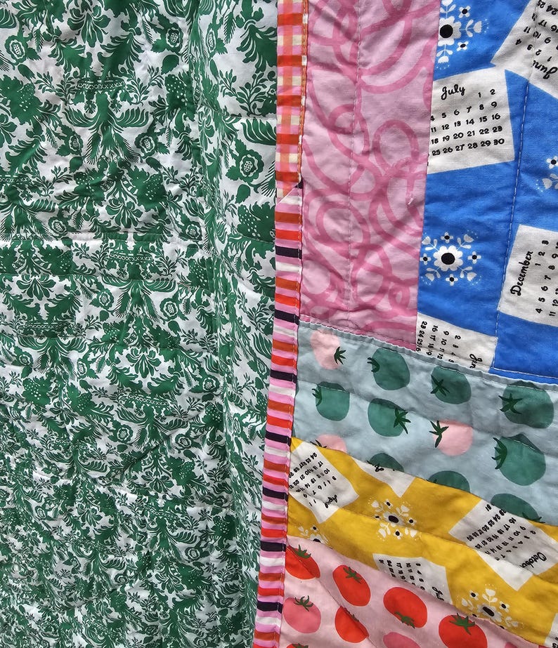 May include: A patchwork quilt with a variety of fabrics and patterns, including green floral, pink, blue, and yellow. The quilt features a calendar design with the months of June, July, and December.