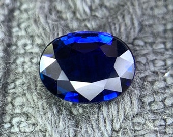Könnte beinhalten: Ein tiefblauer ovaler Saphir-Edelstein mit facettiertem Schliff.