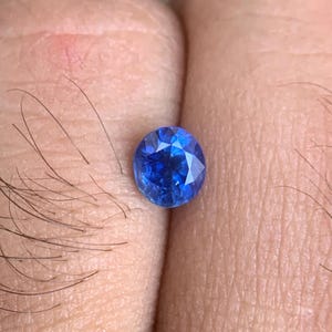 Op de afbeelding: Een levendige blauwe ovale edelsteen met een facetgeslepen vorm.