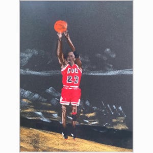 May include: An artistic rendering of a basketball player in a red uniform with the number 23, mid-shot. The player is set against a dark background with a basketball in mid-air. The word "Bulls" is visible on the jersey.