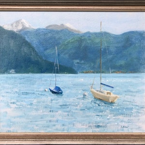 May include: A painting of two sailboats on a lake with mountains in the background. The sky is blue and the water is a light blue. The mountains are covered in snow.