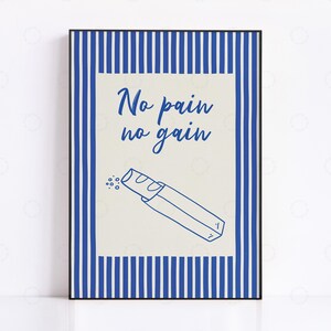 May include: A framed print with a blue and white striped border. The centre features the text "No pain no gain" above a line drawing of a baguette. The background is a light beige colour.