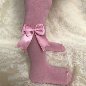 May include: Pink tights with a pink satin bow at the knee.