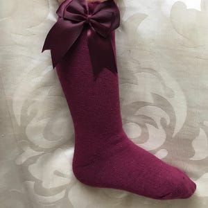 May include: Burgundy knee-high socks with a large burgundy satin bow at the top.