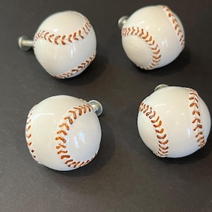 May include: Four baseball-themed cabinet knobs. Each knob is white with red stitching, resembling a baseball. The knobs have a silver-colored stem for mounting. Ideal for a sports-themed room or adding a playful touch to furniture.