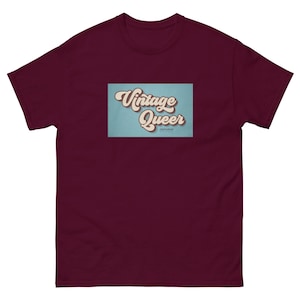 Puede incluir: Una camiseta color granate con un gráfico de estilo vintage que dice "Vintage Queer" en un cuadro azul claro con contorno blanco.