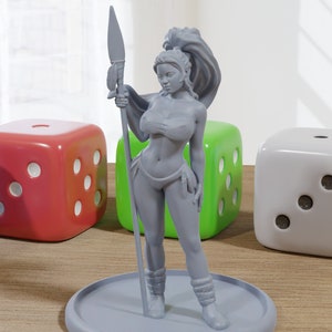 May include: A gray plastic figurine of a woman holding a spear. She is wearing a bikini top and a skirt. The figurine is standing on a round base. There are four dice in the background.