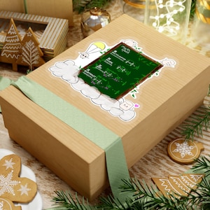 Puede incluir: Una caja de regalo marrón con una pegatina verde y blanca que presenta una pizarra de dibujos animados con las palabras "Math Hack" y ecuaciones matemáticas. La pegatina también incluye personajes de dibujos animados.