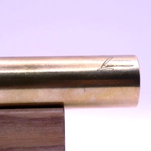 Close-up of the artist's signature or unique design detail etched onto the base of the handmade brass kaleidoscope. Confirms authenticity and collector value.