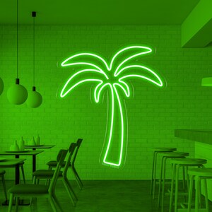 K&ouml;nnte beinhalten: Ein gr&uuml;nes Neon-Palmen-Schild h&auml;ngt an einer Backsteinwand in einem Caf&eacute;. Das Caf&eacute; hat eine Bar mit Hockern und Tische mit St&uuml;hlen. Mehrere gr&uuml;ne Globus-Pendelleuchten h&auml;ngen von der Decke.