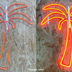K&ouml;nnte beinhalten: Ein orangefarbenes Neon-Palmen-Schild, ausgeschaltet und eingeschaltet, das den Schein der Neonlichter zeigt. Das Schild ist auf einem Holzpaneel-Hintergrund montiert.